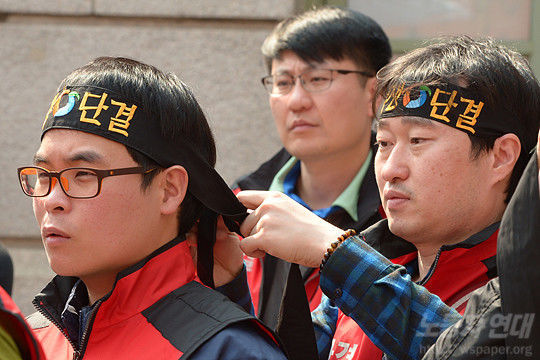 노동조합 동지들이 머리띠를 묶어주며 결의를 다지고 있다.